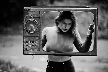 Fashion portrait of redhaired sexy girl outdoor. Model attractive dramatic woman with old tv box.