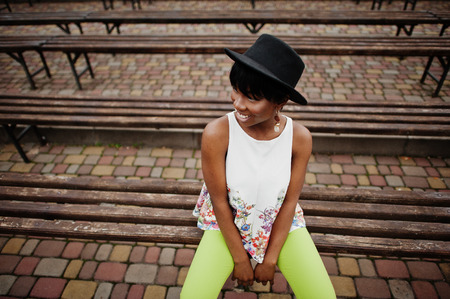 Amazing african american model woman in green pants and black hat posed at bench.の写真素材