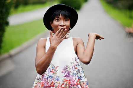 Amazing african american model woman in green pants and black hat posed with different emotions at park, shows a surprise face.の写真素材