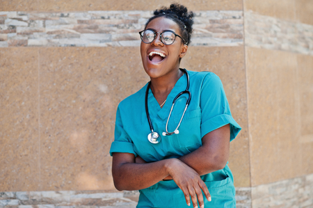 African american doctor female at lab coat with stethoscope posed outdoor against clinic.の写真素材
