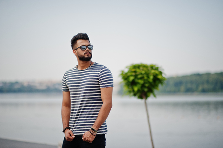 Handsome tall arabian beard man model at stripped shirt posed outdoor. Fashionable arab guy at sunglasses.の写真素材