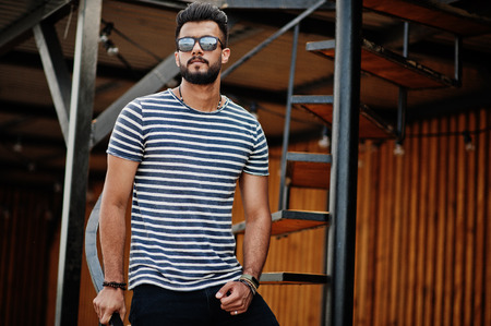 Handsome tall arabian beard man model at stripped shirt posed outdoor. Fashionable arab guy at...