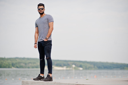 Handsome tall arabian beard man model at stripped shirt posed outdoor. Fashionable arab guy at sunglasses.の写真素材