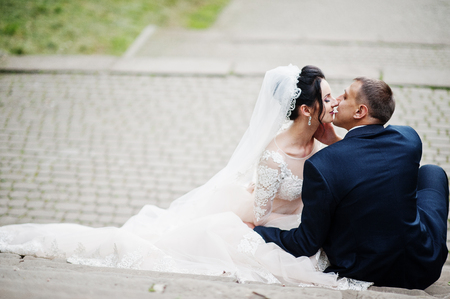 Close-up photo of wedding couple sitting and kissing in the park.の写真素材