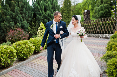 Newly married couple walking in the park on the sunny summer wedding day.の写真素材