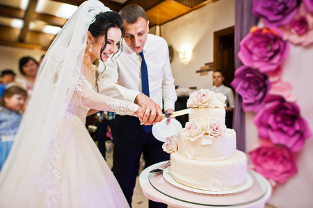 Wedding couple cutting their gorgeous white wedding cake in the restaurant.の写真素材