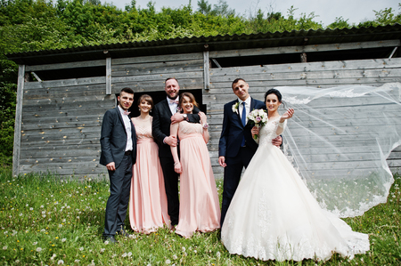 Bridesmaids with groomsmen and wedding couple having fun outdoors next to the old rustic wooden barn.の写真素材