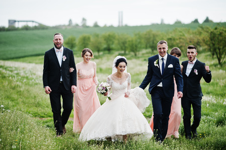 Groomsmen with bridesmaids and wedding couple walking on the flower field.の写真素材
