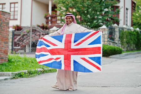 Middle Eastern arab man posed on street with Great Britain flag. England and Arabian countries concept.の写真素材