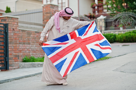 Middle Eastern arab man posed on street with Great Britain flag. England and Arabian countries concept.の写真素材