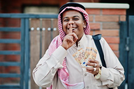 Middle Eastern arab business man posed on street against modern building with black handbag and euro...