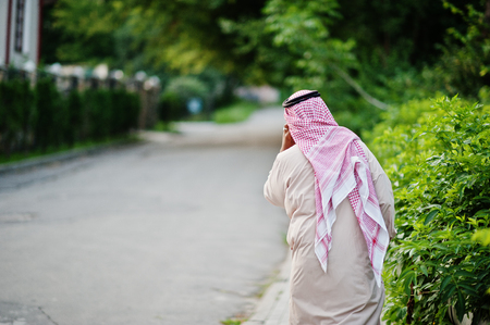 Back of Middle Eastern arab business man posed on street speaking on mobile phone.の写真素材