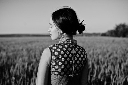 Tender indian girl in saree, with violet lips make up posed at field in sunset. Fashionable india model.の写真素材