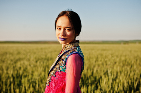 Tender indian girl in saree, with violet lips make up posed at field in sunset. Fashionable india model.の写真素材