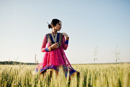Tender indian girl in saree, with violet lips make up posed at field in sunset. Fashionable india model.の写真素材