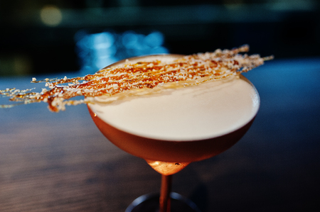 Alcoholic cocktail with fused sugar in bronze glass on bar table.の写真素材