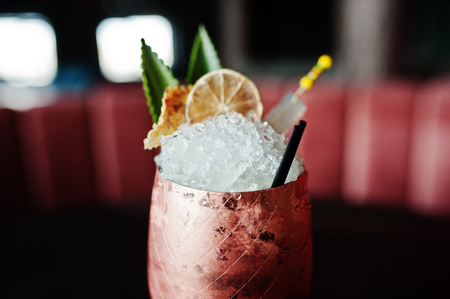 Alcoholic cocktail with ice in bronze glass on bar table.の写真素材