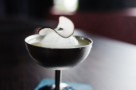 Alcoholic cocktail with ice and coconut in silver glass on bar table.の写真素材