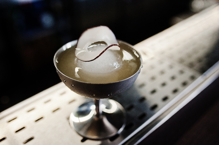 Alcoholic cocktail with ice and coconut in silver glass on bar table.の写真素材