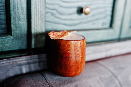 Alcoholic cocktail in wooden cup at  bar table.