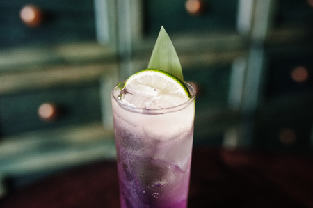 Alcoholic long violet cocktail with ice in glass at bar table.の写真素材