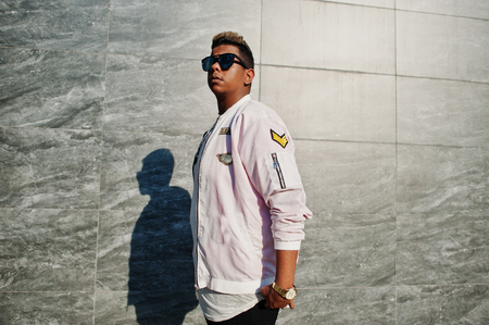Stylish hipster arab man guy in sunglasses posed outdoor in street at sunset against gray wall.の写真素材