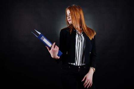 Portrait of a redheaded businesswoman wearing striped blouse, glasses and a jacket with a blue folder.の写真素材