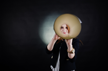 Portrait of a redheaded businesswoman in striped blouse and jacket looking through the paper tube.の写真素材