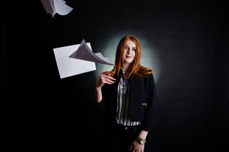 Portrait of a redheaded businesswoman in striped blouse and jacket throwing the paper away.の写真素材