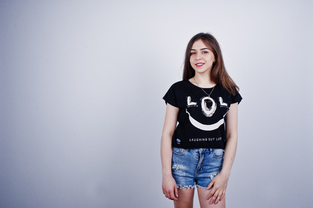 Portrait of an attractive girl in black t-shirt saying lol and denim shorts posing in the studio.の写真素材
