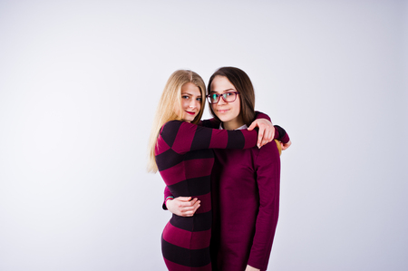 Portrait of two female friends in cherry dresses posing in the studio.の写真素材