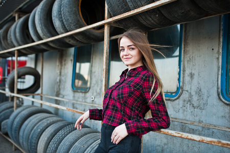 Young hipster girl in checkered shirt at tire fitting zone.の写真素材