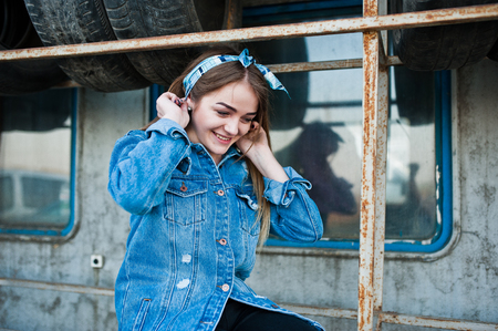 Young hipster girl in jeans jacket and head scarf at tire fitting zone.の写真素材