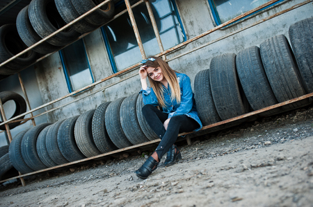 Young hipster girl in jeans jacket and head scarf at tire fitting zone.の写真素材