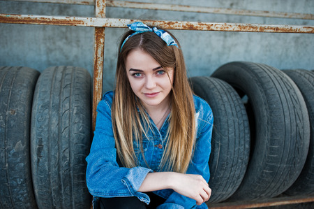 Young hipster girl in jeans jacket and head scarf at tire fitting zone.の写真素材
