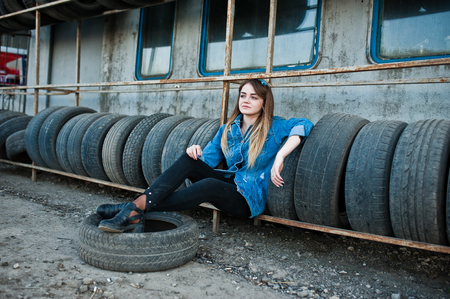 Young hipster girl in jeans jacket and head scarf at tire fitting zone.の写真素材