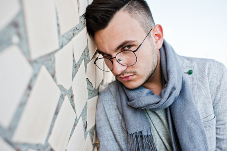 Dreamer stylish macho man in gray suit, scarf and glasses posed on the roof.の写真素材