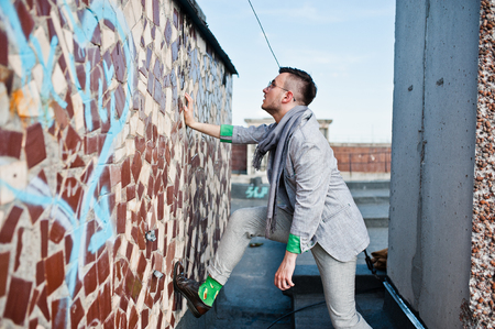 Dreamer stylish macho man in gray suit, scarf and glasses posed on the roof.の写真素材