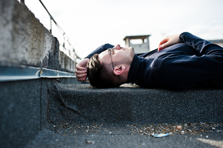 Dreamer stylish macho man in black golf and glasses posed on the roof.の写真素材