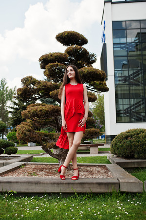Teenage girl in red dress posed outdoor at sunny day.の写真素材