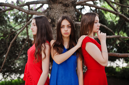 Three teenagers girl in blue and red dresses posed outdoor.の写真素材