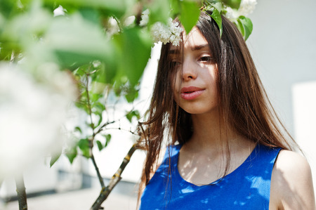 Teenage girl in blue dress posed outdoor at sunny day.