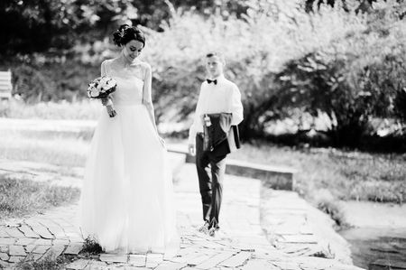 Young newlyweds walking in the park on their sunny wedding day. Black and white photo.の写真素材