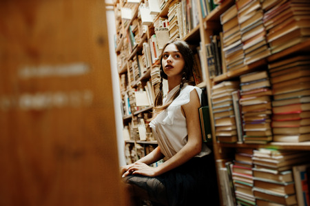 Girl with pigtails in white blouse at old library.