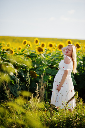 Blonde pregnant mother in sunflowers field. Happy moments of pregnancy.の写真素材