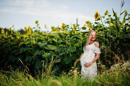 Blonde pregnant mother in sunflowers field. Happy moments of pregnancy.の写真素材