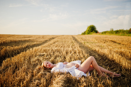 Blonde pregnant woman in wreath field at white underwear clothes on sunset. Happy moments of pregnancy.の写真素材