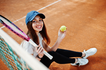 Young sporty girl player with tennis racket on tennis court.の写真素材