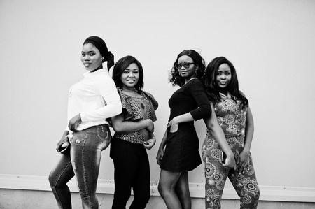 Group of four african american girls posed outdoor against wall.