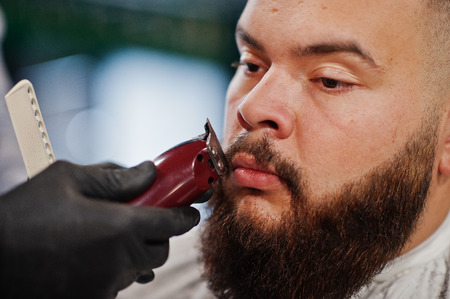 Handsome bearded man at the barbershop, barber at work.